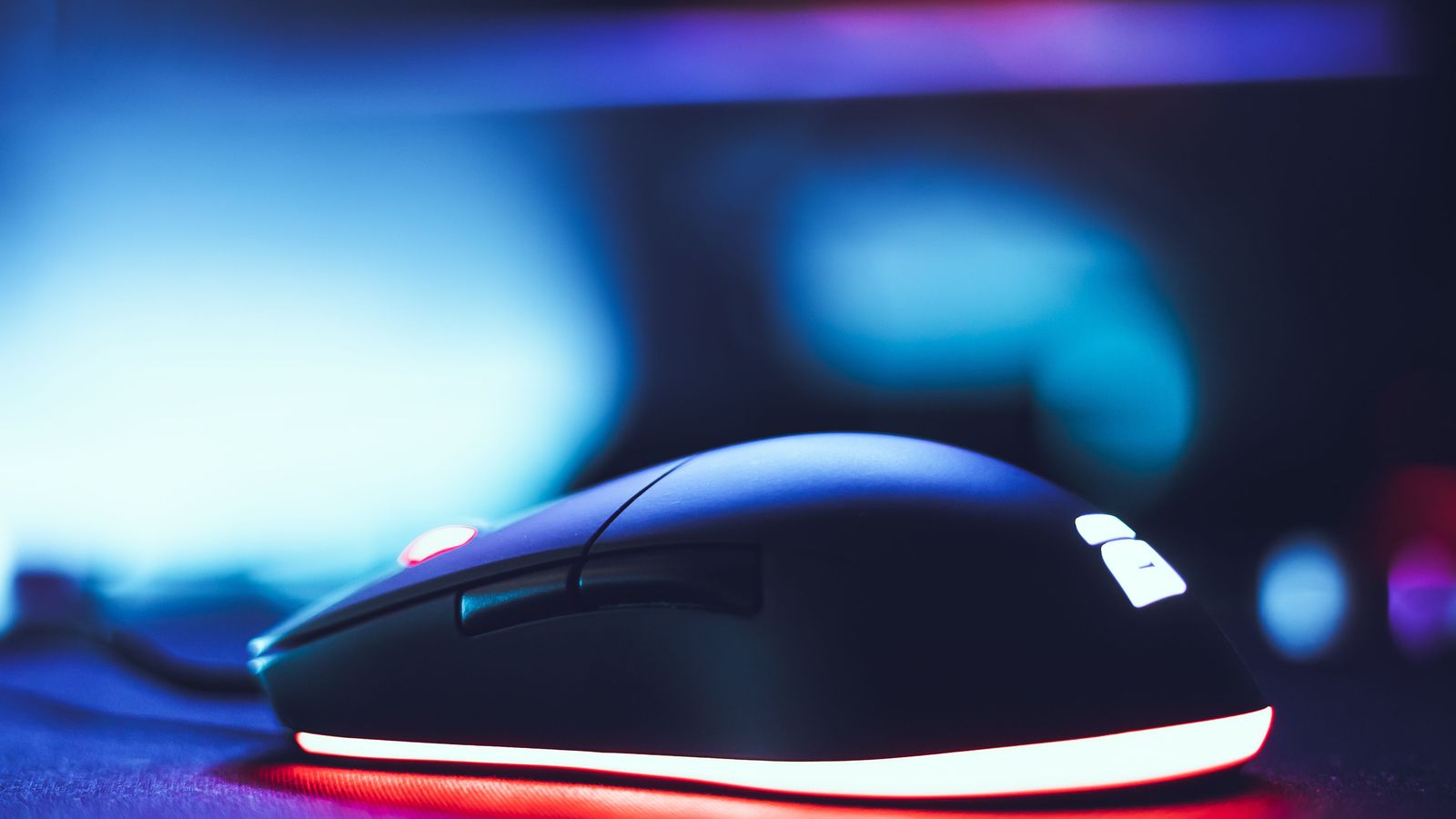 Close-up of a black gaming mouse with red and white LED glow.